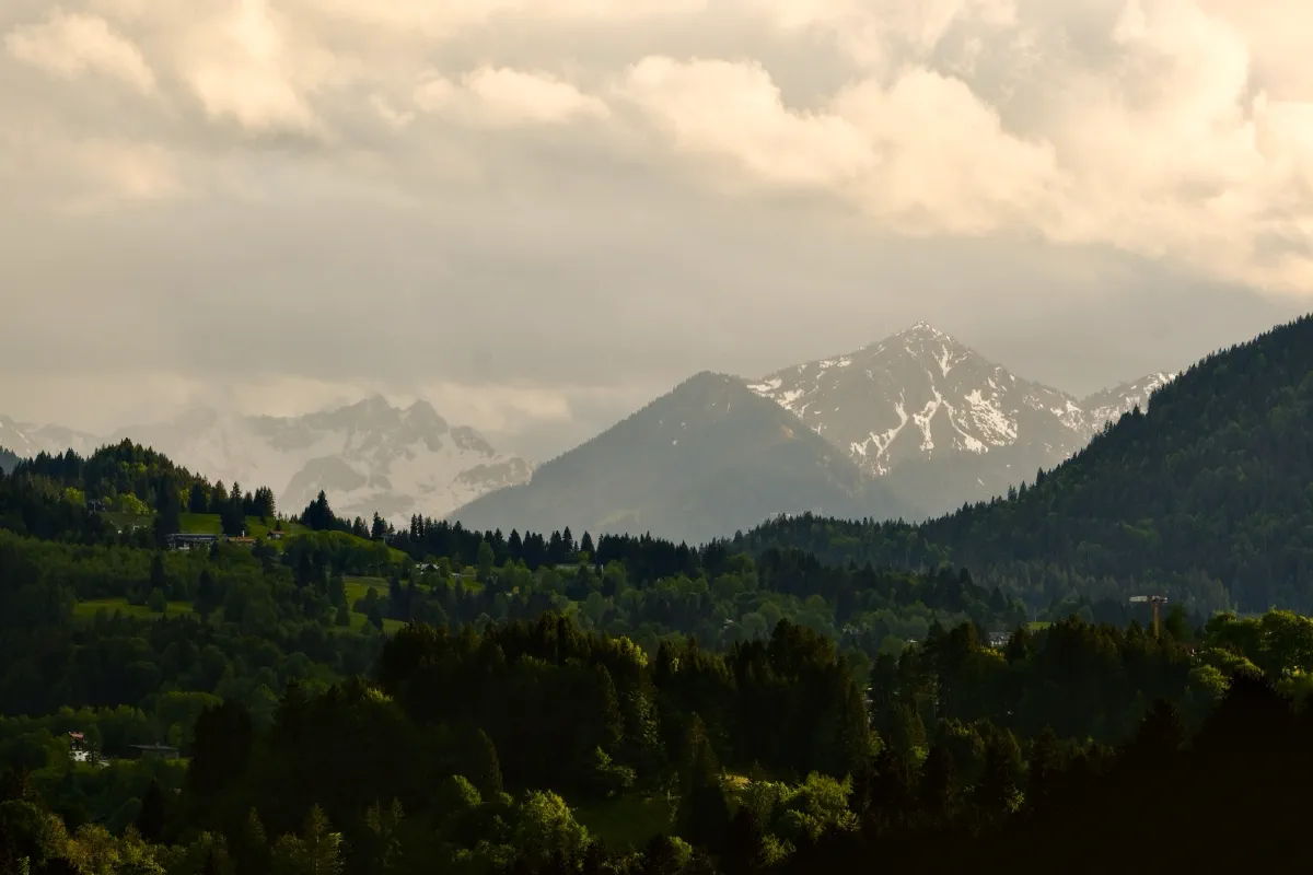Bergkette im Abendlicht, schneebedeckte Gipfel unter einem hohen Wolkenhimmel