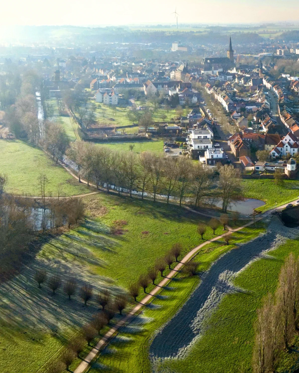 Luftaufnahme von Kalkar mit Kirche und Mühlenturm im Ortskern, davor Wiesen, eine Kopfweidenreihe und ein Bachlauf